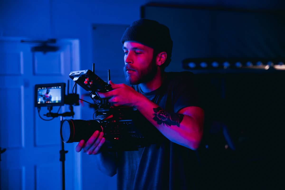 Videographer operating a cinema rig under neon light